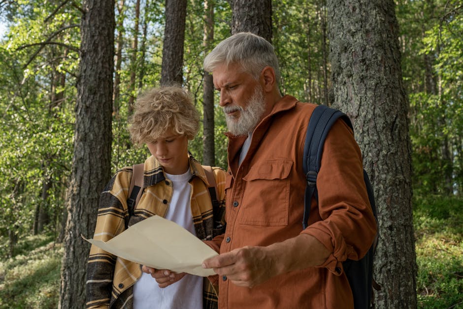 Grandfather and grandson navigate with a map while hiking in a lush forest.